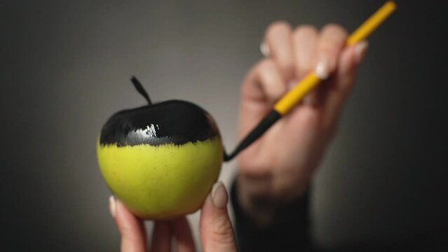 the girl paints a green apple in a matte black color.negative consequences of emotions. High quality Full HD video recording