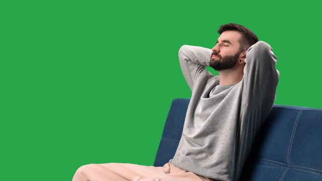 Relaxed man stress free sitting on couch with hands behind head closed eyes chroma key green screen