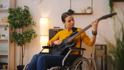 Young woman in wheelchair playing electric guitar at home, musical performance