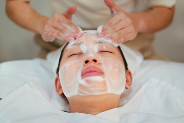 Crop beautician doing facial cleansing procedure