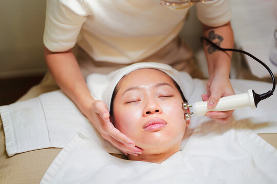 Crop beautician doing microcurrent therapy