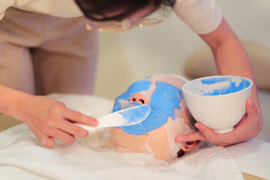 Crop beautician applying alginate mask