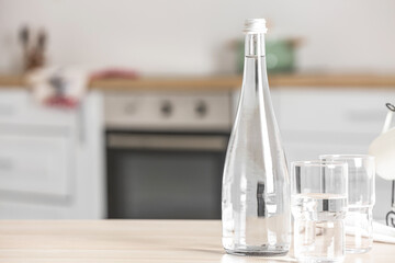 Bottle of water and glasses on table in kitchen