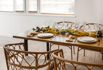 Beautiful table setting with mimosa flowers and candles in room