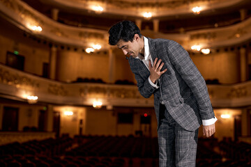 man Presenter in elegant classic suit on Stage is expressing gratitude to audience after...