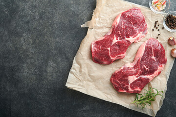 Raw beef steak. Marbled raw fresh Ribeye steak with rosemary, salt and pepper on cutting board on...