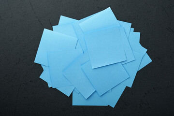 Blue paper stickers on black background. Sticky notes blank with copy space ready for your message. New year goals or resolutions concept. Blue Monday idea. Flat lay copy space on black background.