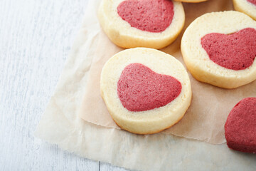 Valentines day cookies. Shortbread cookies inside a sweet red heart on parchment paper on white background. Mothers day. Womans day. Sweet holidays baking. Top view.