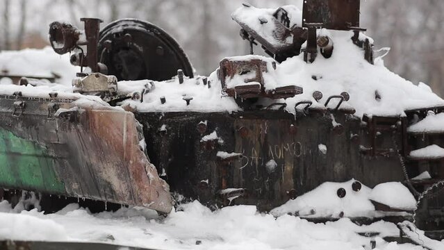 Kyiv, Ukraine - December 15, 2022: Burnt part of a rusty burnt russian tank T-72, covered with snow, close-up on the street. Burnt russian military equipment in the center of Kyiv. War in Ukraine.