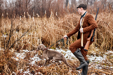Hunting period, autumn season open. confident young caucasian hunter with dog, gun in hands in...