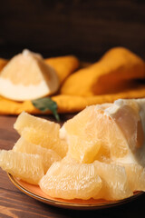Plate with sweet slices of pomelo fruit on wooden table, closeup