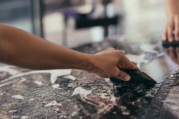 Hand of detailing film paint protection men specialist cleaning and wrapping car in garage showroom, protective coating installation and polishing automobile for vehicle care service business concept