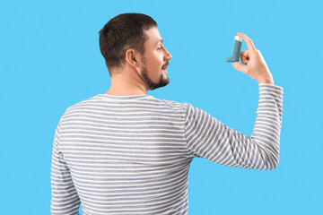 Man with inhaler on blue background