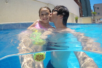 pai e filha se divertindo na piscina mergulho 
