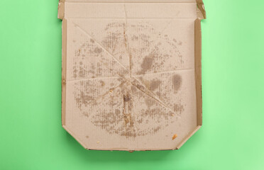 Empty greasy pizza box on green background