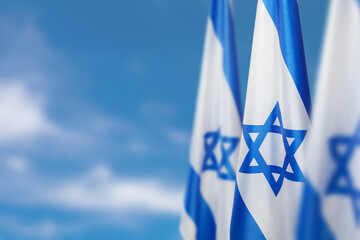 Israel flags with a star of David over cloudy sky background. Patriotic concept about Israel with...