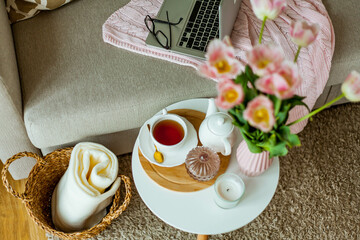 Home cozy office. Work at home. Spring decor. Knitted blanket, bouquet of tulips, hot tea, laptop. Freelance.