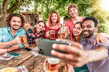 Happy friends drinking beer at outdoor brewery bar - Group of multiracial people taking selfie...