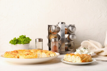 Plates with delicious cheese pie and ingredients on white table