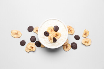 Bowl with delicious rice pudding, banana slices and chocolate chips on white background