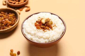 Bowl with delicious rice pudding, raisins and cashew on beige background