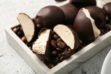 Board with tasty bird's milk candies and coffee beans on light background