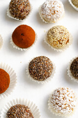 Assorted Vegan Sweets, Delicious Candy Balls with seeds, nuts and cocoa powder, Healthy Candies on Bright Background
