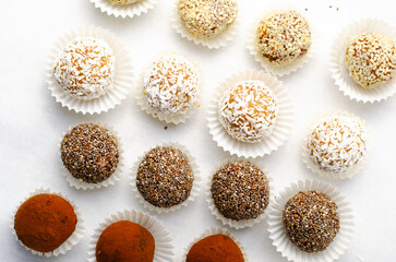 Assorted Vegan Sweets, Delicious Candy Balls with seeds, nuts and cocoa powder, Healthy Candies on Bright Background