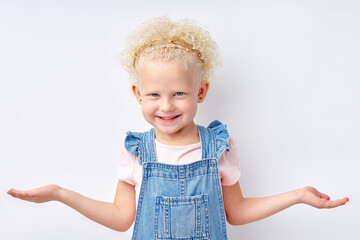 Little caucasian blonde confused mistaken kid nice girl 5 years old spreading hands oops gesture look camera isolated on white studio background, children. Childhood lifestyle concept