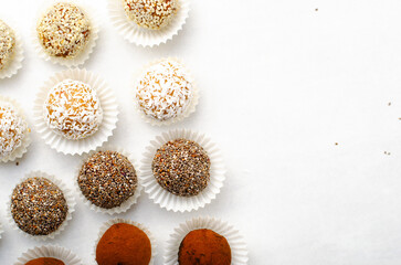 Assorted Vegan Sweets, Delicious Candy Balls with seeds, nuts and cocoa powder, Healthy Candies on Bright Background