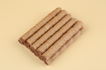Heap of of tasty wafer rolls with boiled condensed milk on beige background