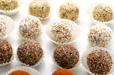 Assorted Vegan Sweets, Delicious Candy Balls with seeds, nuts and cocoa powder, Healthy Candies on Bright Background