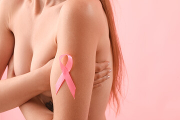 Naked young woman with pink ribbon on color background, closeup. Breast cancer awareness concept