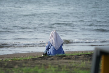 A woman sitting on the beach enjoying the sea view