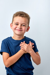 Close up of cute happy small boy isolated on white studio background hold hands at heart chest feel...