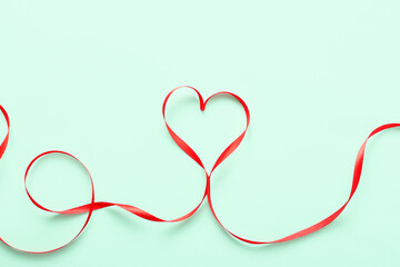 Heart made of red ribbon on green background. Valentine's Day celebration