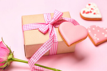 Gift box, rose flower and heart shaped cookie on pink background, closeup. Valentine's Day celebration