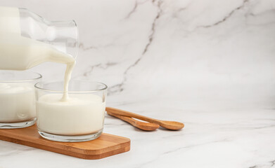Pouring yogurt in glass on a light background. Healthy, clean eating. Vegan or gluten free diet