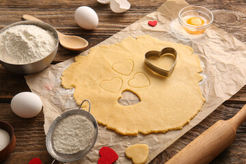 Fototapeta na wymiar Raw dough and ingredients for preparing tasty cookies on wooden background. Valentines Day celebration