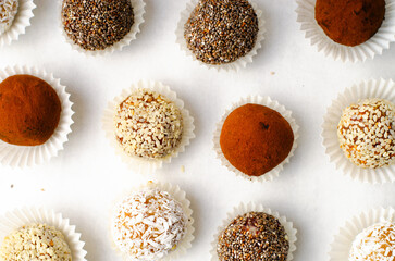 Assorted Vegan Sweets, Delicious Candy Balls with seeds, nuts and cocoa powder, Healthy Candies on Bright Background