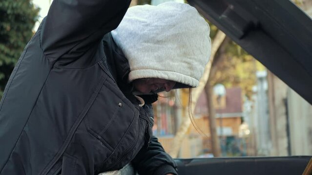 Hungry homeless man rummaging in trash can looking for food.