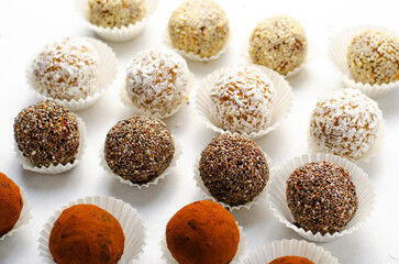 Assorted Vegan Sweets, Delicious Candy Balls with seeds, nuts and cocoa powder, Healthy Candies on Bright Background