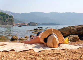 Woman in a straw hat sunbathes on the beach of Budva, Montenegro