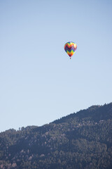 Colorful hot air balloon flying over mountain with clear sky and copy space