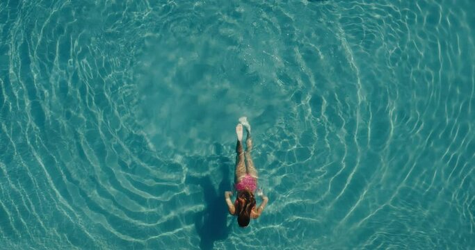 Aerial view of beautiful woman swimming in the the pool at luxury resort spa
