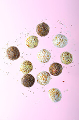 Levitating Vegan Sweets, Delicious Candy Balls with seeds, nuts and dried fruit, Healthy Candies on Pink Background