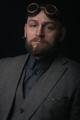 charismatic man in a classic suit and steampunk goggles on a black background stylish Portrait