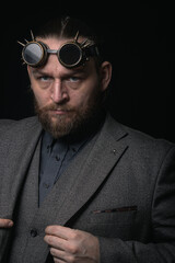 Fototapeta premium charismatic man in a classic suit and steampunk goggles on a black background stylish Portrait