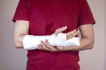 Broken arm, fingers. A white man in a red T-shirt with a cast on his arm.