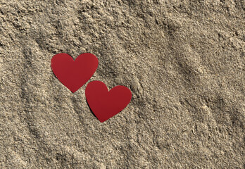 Two red hearts lie on the sand. Valentine's Day. soft focus
